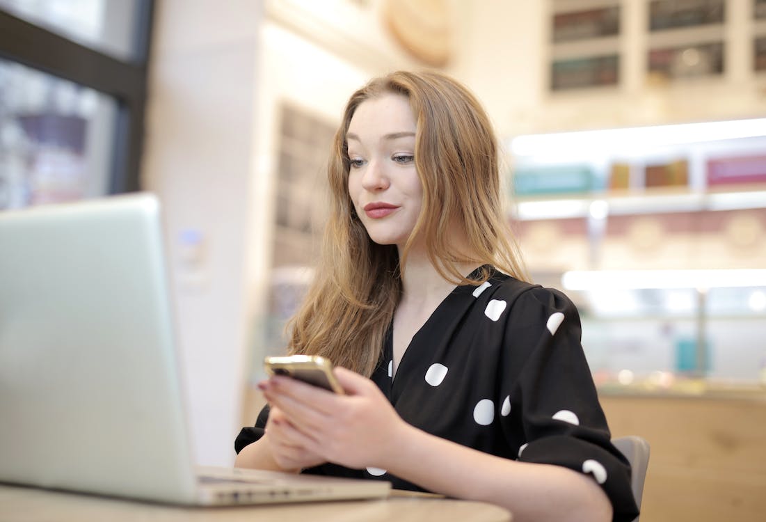 Free Woman in Black and White Polka Dot Dress Using Portable Computer Stock Photo