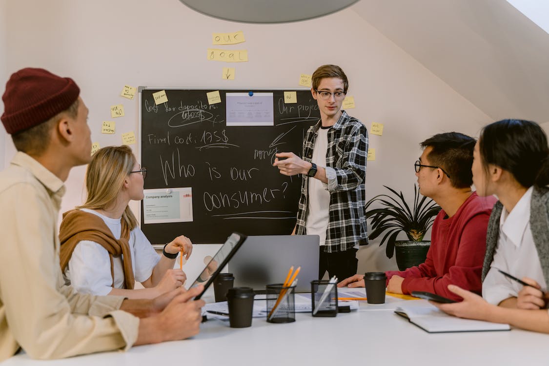 Free Man in Plaid Long Sleeve Shirt Presenting in a Meeting Stock Photo